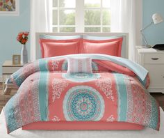 a bed in a room with blue walls and pink comforter set on top of it