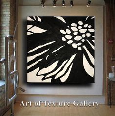 a large black and white flower painting hanging on the wall in a room with brick walls