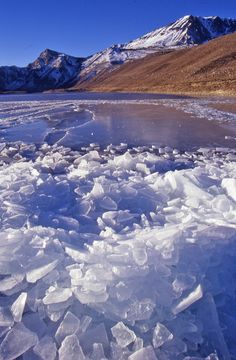 an icy lake with mountains in the background