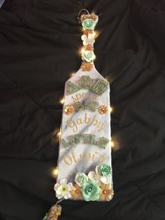 a bottle that is decorated with flowers and the words happy birthday written in gold on it