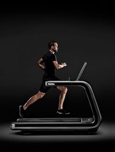 a man is running on a treadmill with a laptop in his hand and he is looking at the screen