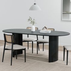 a dining table with four chairs and a vase on the table in front of it