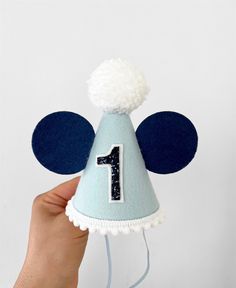 Party hat is made of - baby blue merino felt - white pom - white pompom trim - elastic band - baby blue ears - white/navy blue layered age number Size is H 12 cm W 8 cm Please  make sure the size meets your expectations before ordering IMPORTANT: Please do not give it to the baby or kids to play with. It can cause choking due to small particles or decorations. So please take that granted. THANK YOU Kindly note: Make sure your address is correct during checkout to avoid product loss Returns and e Felt Party Hat, Blue Mouse, Hat Cake, Mickey Mouse Birthday, Birthday Hat, Blue Hat, Party Hat, Cake Smash, Party Hats