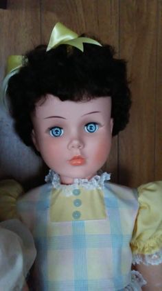 the doll is wearing a yellow dress with blue eyes and a bow in her hair