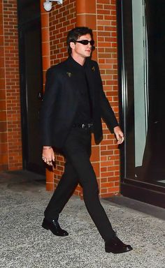 a man in a black suit and sunglasses walking down the street