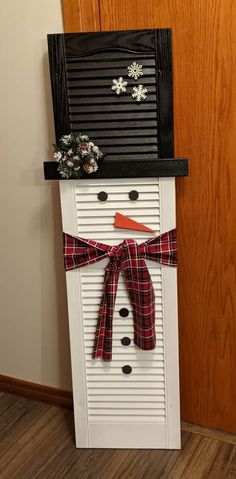 a snowman made out of shutters and ribbon