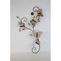 a metal wall sculpture with butterflies and flowers on it's side, against a white background