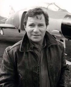 black and white photograph of a man standing in front of an airplane with another plane behind him