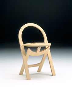 a wooden chair sitting on top of a white floor next to a black wall in the background