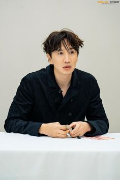 a young man sitting at a table with his hands folded