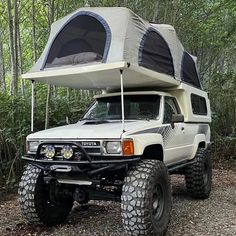 an off road camper is parked in the woods with its tent on it's roof