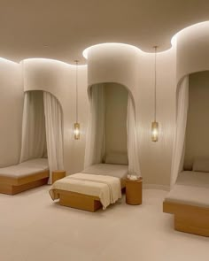 three beds in a room with white walls and drapes hanging from the ceiling above them