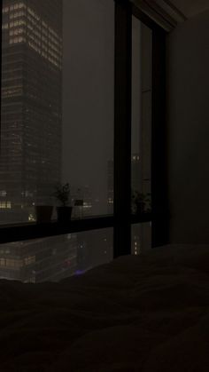 a bedroom with a view of the city at night from it's window sill