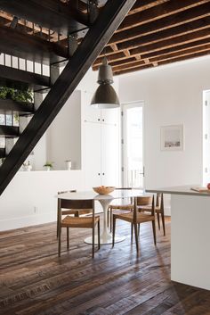 an open kitchen and dining area with wooden floors, white walls, and stairs leading up to the second floor