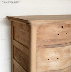 a close up of a wooden dresser against a white wall