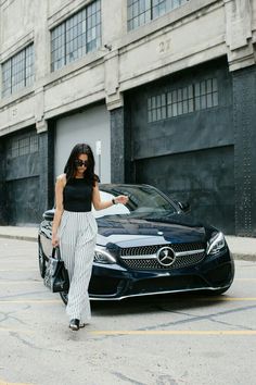 a woman standing next to a black car