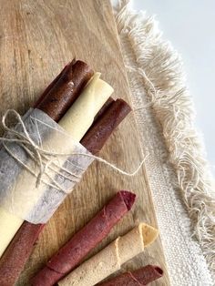 four sausages wrapped in wax paper on a cutting board