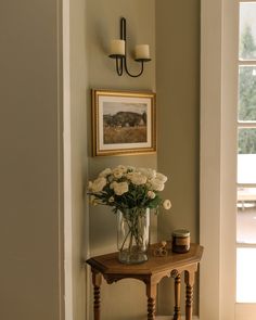 a vase filled with white flowers sitting on top of a table next to a doorway