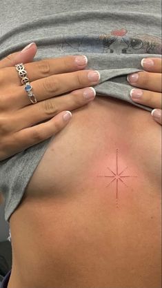 a woman's stomach with a small cross tattoo on the back of her belly