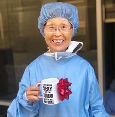 an older woman in scrubs holding a coffee mug