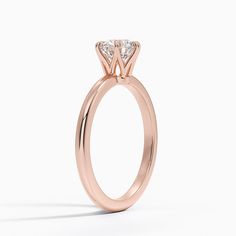 a rose gold engagement ring with a princess cut diamond in the center, on a white background