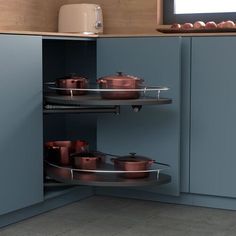 an open cabinet with pots and pans on the bottom shelf in a kitchen area