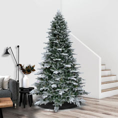 a white christmas tree in the corner of a living room with stairs and a couch