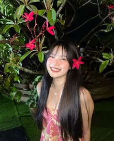 a woman standing in front of a tree with red flowers on it's head