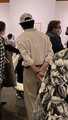 people are standing in line at an art show with masks on their faces and one person is wearing a face mask