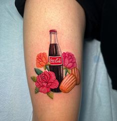 a woman's thigh with a coca cola and flowers tattoo on her left calf