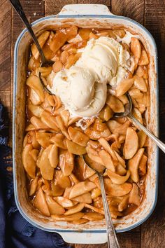 an apple cobbler with ice cream on top and spoons in the casserole