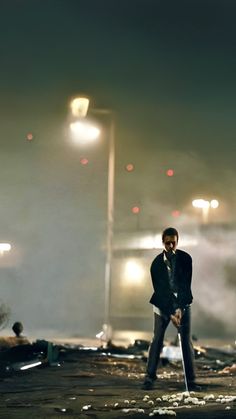 a man standing in the middle of an empty parking lot at night with lights on