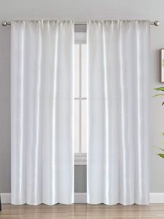 a white curtain hanging on the side of a window in front of a potted plant