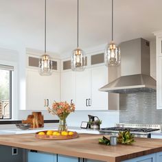 a kitchen with blue cabinets and an island in front of a stove top oven surrounded by hanging lights