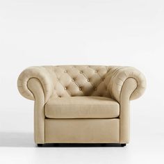 a beige leather chair with buttons on the armrests and foot rest in front of a white wall