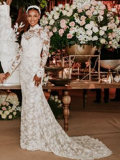 a woman in a wedding dress standing next to a table with flowers and candles on it