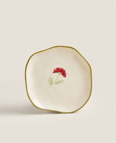 a white plate with a red flower on it