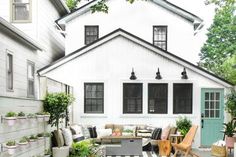 an outdoor living area with furniture and potted plants on the side of the house