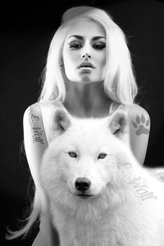 a woman with tattoos on her arm next to a white wolf in black and white