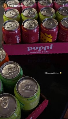 many cans of soda are in a pink box on a table next to a black surface