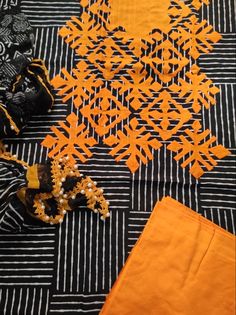 an orange and black piece of cloth on top of a striped tablecloth with beads