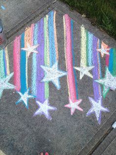 someone is standing on the sidewalk with chalk stars painted on it and there are pink, purple, blue, green, orange and white stripes