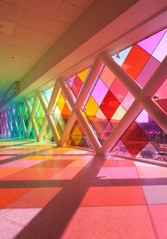 an abstract photo of colorful glass windows in a building with white columns and flooring