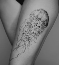 a woman's thigh with flowers and a jellyfish tattoo on her left leg