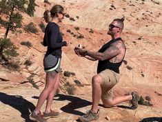 a man and woman standing on top of a cliff