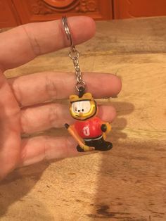 a hand holding a keychain with a cartoon character on it's side