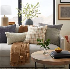 a living room filled with lots of pillows and blankets on top of a white couch