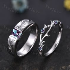 two silver rings with blue topazte and white sapphire stones on them, sitting on a black surface