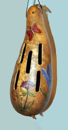 a decorative hanging object with flowers and butterflies on it's side, in the shape of a pear