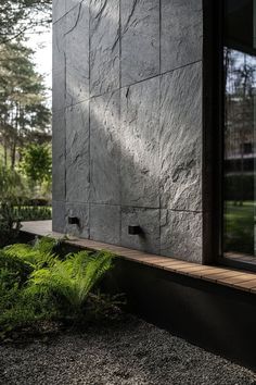 an exterior view of a house with stone walls and plants in the foreground,